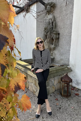 a lady in a black knit top, a striped sweater jacket and a pair of black pants